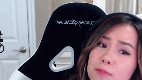 A Woman Is Sitting In A Black And White Gaming Chair With The Word Jxc On The Back GIF