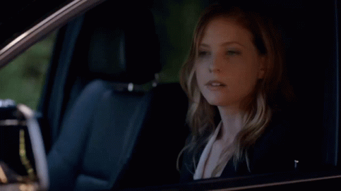 A Woman Is Sitting In A Car And Pointing GIF