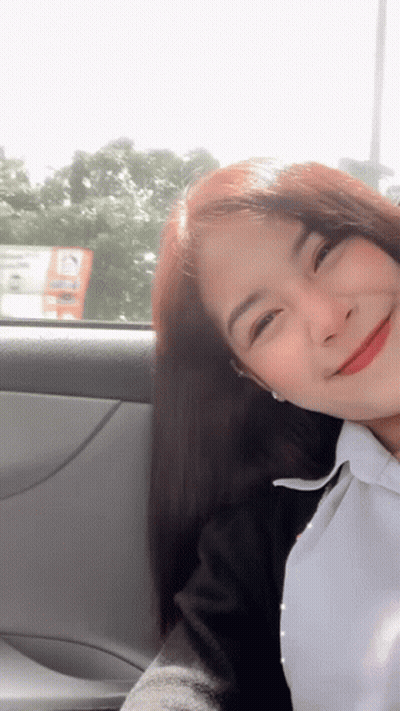 A Woman Is Sitting In A Car And Smiling GIF