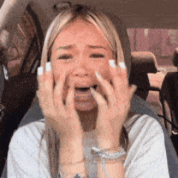 A Woman Is Sitting In A Car Covering Her Mouth With Her Hands GIF