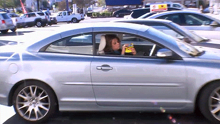 A Woman Is Sitting In A Car Drinking A Beer GIF