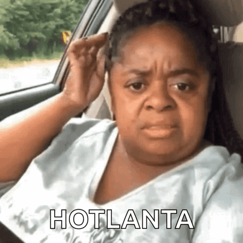 A Woman Is Sitting In A Car With Her Hand On Her Ear And The Words Hotlanta Written On The Bottom . GIF