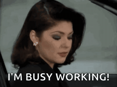 A Woman Is Sitting In A Car With The Words `` I 'M Busy Working '' Written On Her Face . GIF