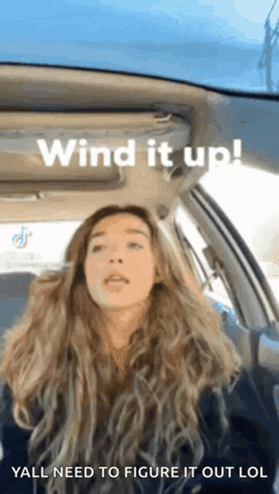 A Woman Is Sitting In A Car With The Words Wind It Up GIF