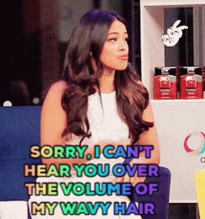 A Woman Is Sitting In A Chair And Says Sorry I Can 'T Hear You Over The Volume Of My Wavy Hair .. GIF