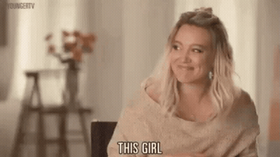 A Woman Is Sitting In A Chair And Smiling While Talking To Someone . GIF