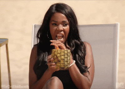 A Woman Is Sitting In A Chair Holding A Pineapple And Drinking From It . GIF