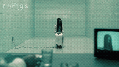 A Woman Is Sitting In A Chair In A Room With The Word Rings Written On The Wall GIF