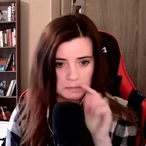 A Woman Is Sitting In A Chair In Front Of A Microphone And Making A Funny Face . GIF