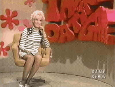 A Woman Is Sitting In A Chair In Front Of A Wall That Says Mbs GIF