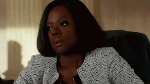 A Woman Is Sitting In A Chair In Front Of A Window And Looking At The Camera . GIF