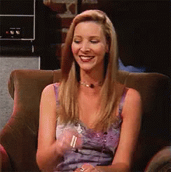 A Woman Is Sitting In A Chair Smiling And Clapping Her Hands GIF