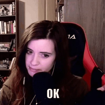A Woman Is Sitting In A Chair With A Microphone In Front Of Her And The Word Ok Is On Her Face . GIF