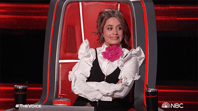 A Woman Is Sitting In A Chair With Her Arms Crossed And A Flower In Her Mouth .. GIF