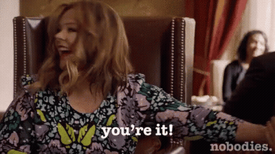 A Woman Is Sitting In A Chair With Her Arms Outstretched And Says `` You 'Re It '' . GIF