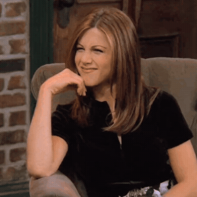 A Woman Is Sitting In A Chair With Her Hand On Her Chin And Smiling GIF