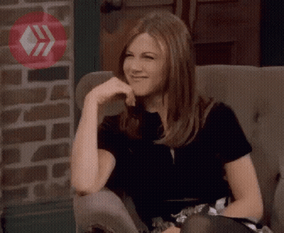 A Woman Is Sitting In A Chair With Her Hand On Her Chin And Smiling GIF