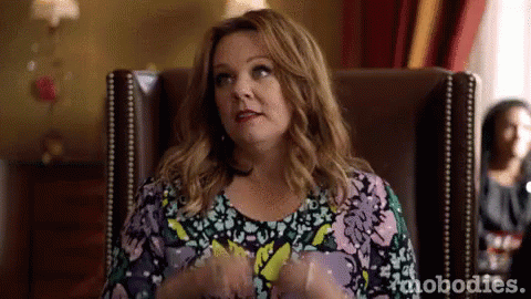 A Woman Is Sitting In A Chair With Her Hands In Her Pockets And Making A Funny Face . GIF