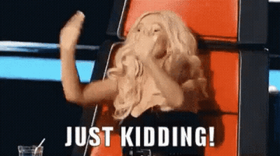 A Woman Is Sitting In A Chair With Her Hands In The Air And The Words `` Just Kidding ! '' Above Her . GIF