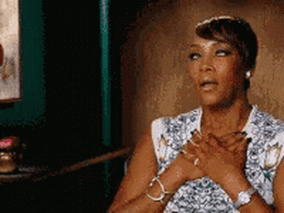 A Woman Is Sitting In A Chair With Her Hands On Her Heart . GIF