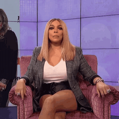 A Woman Is Sitting In A Chair With Her Legs Crossed And A Serious Look On Her Face . GIF
