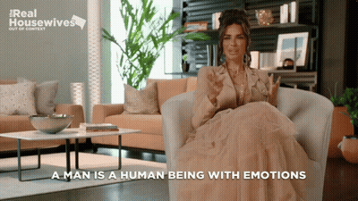 A Woman Is Sitting In A Chair With The Words " A Man Is A Human Being With Emotions " GIF