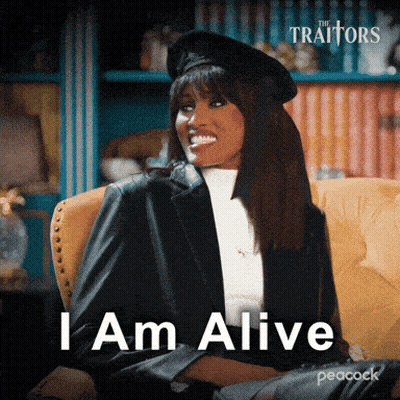 A Woman Is Sitting In A Chair With The Words " I Am Alive " On The Screen GIF