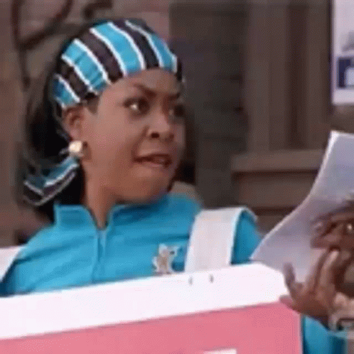 A Woman Is Sitting In A Cooler Holding A Piece Of Paper And Making A Face . GIF