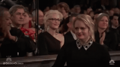 A Woman Is Sitting In A Crowd Of People Applauding At A Awards Ceremony . GIF