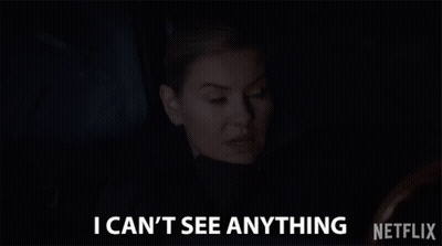 A Woman Is Sitting In A Dark Room And Says `` I Can T See Anything '' . GIF