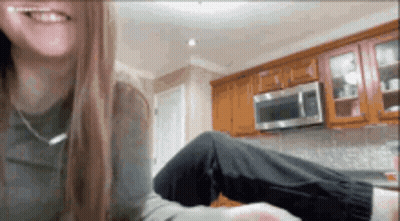 A Woman Is Sitting In A Kitchen With Her Legs Crossed And Smiling . GIF