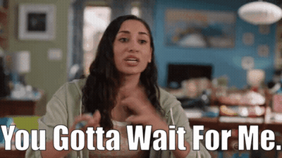 A Woman Is Sitting In A Living Room And Saying " You Gotta Wait For Me " GIF