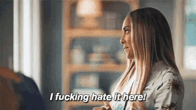 A Woman Is Sitting In A Living Room Talking To A Man And Says `` I Fucking Hate It Here ! '' GIF