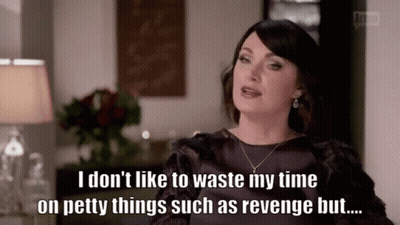 A Woman Is Sitting In A Living Room With A Lamp And A Vase Of Flowers . GIF
