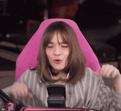 A Woman Is Sitting In A Pink Chair With Headphones On Her Ears . GIF