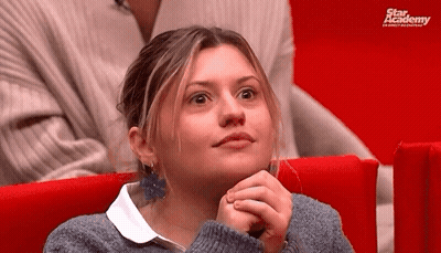 A Woman Is Sitting In A Red Chair With Her Hands On Her Chin . GIF