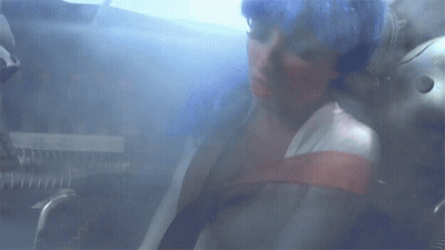 A Woman Is Sitting In A Room With A Smoke Coming Out Of Her Mouth GIF