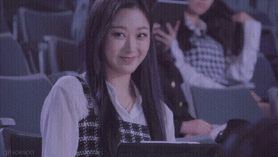 A Woman Is Sitting In A Theater With A Tablet In Her Lap And Smiling . GIF