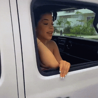 A Woman Is Sitting In A White Van And Looking Out The Window GIF