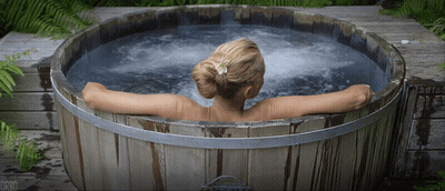 A Woman Is Sitting In A Wooden Tub With The Letters Dr80 On The Bottom GIF
