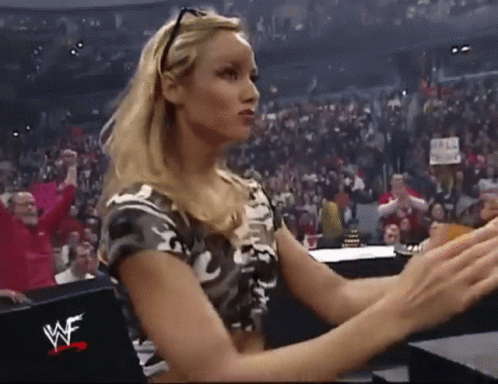 A Woman Is Sitting In A Wrestling Ring With A Wwe Logo On The Back Of Her Shirt . GIF