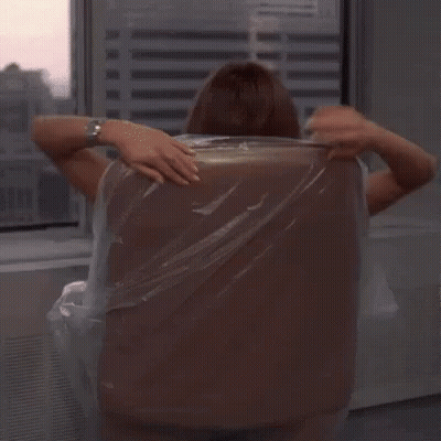 A Woman Is Sitting In An Office Chair With Her Legs Crossed And Holding A Plastic Bag . GIF