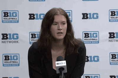 A Woman Is Sitting In Front Of A Big Network Sign GIF