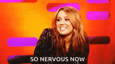 A Woman Is Sitting In Front Of A Colorful Background And Smiling . GIF