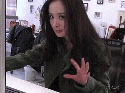 A Woman Is Sitting In Front Of A Laptop Computer And Making A Funny Face . GIF