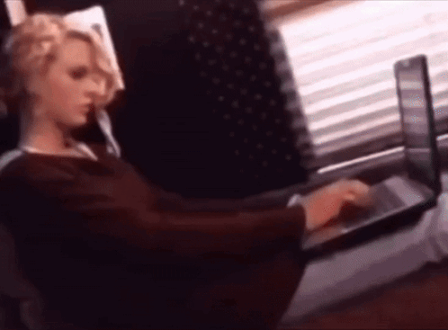 A Woman Is Sitting In Front Of A Laptop Computer . GIF