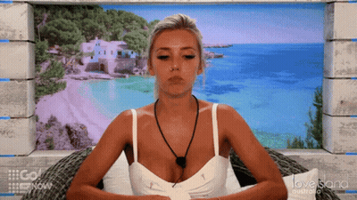 A Woman Is Sitting In Front Of A Love Island Australia Poster GIF