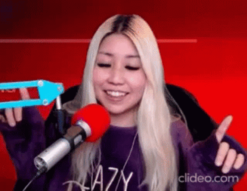 A Woman Is Sitting In Front Of A Microphone And Smiling . GIF