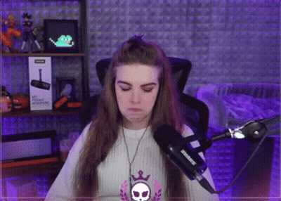 A Woman Is Sitting In Front Of A Microphone With A Skull Necklace Around Her Neck GIF