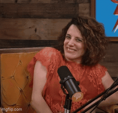 A Woman Is Sitting In Front Of A Microphone With Her Eyes Closed And Her Hands In The Air GIF